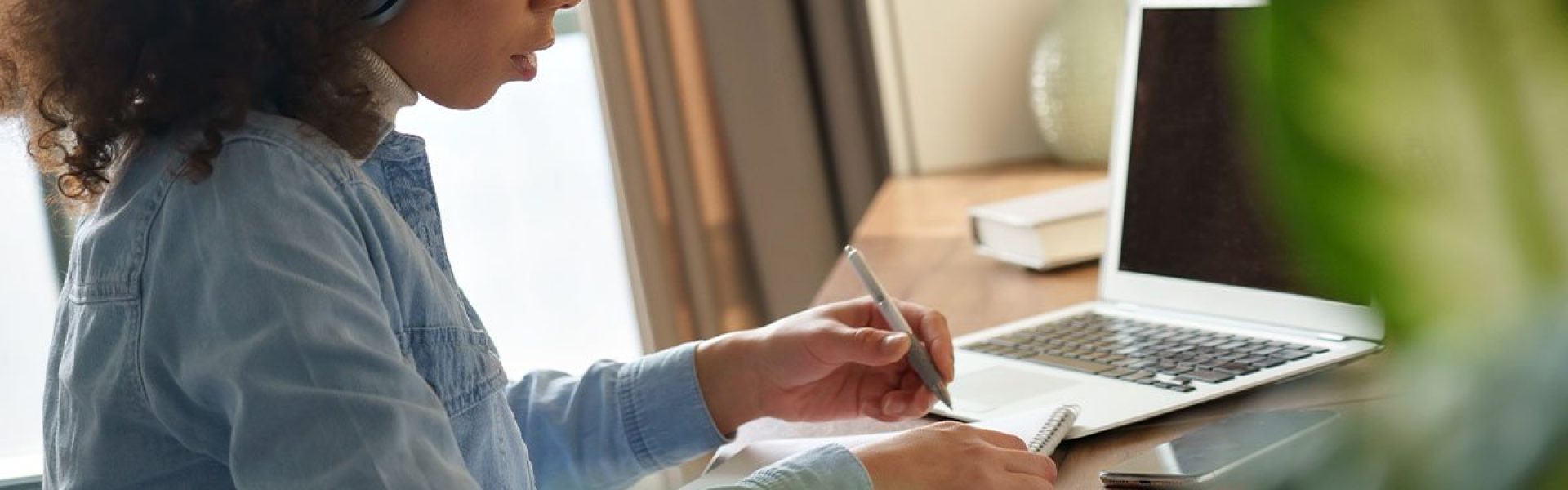 Student taking notes in front of laptop